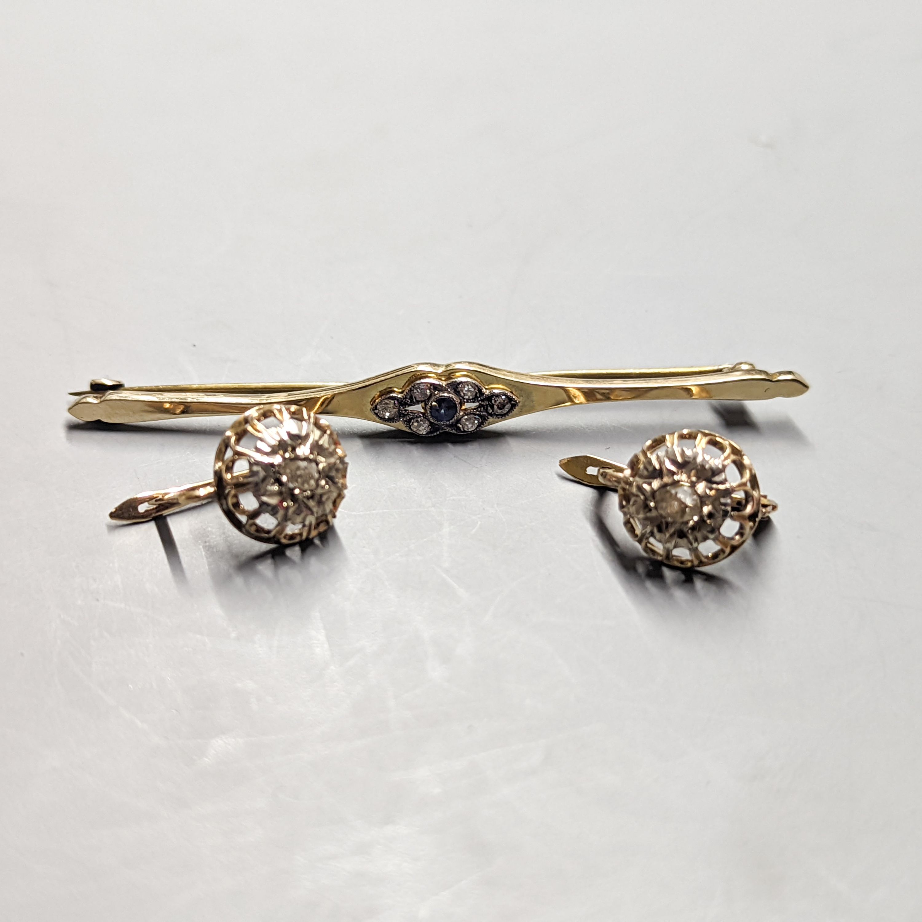 A pair of yellow metal and solitaire illusion set rose cut diamond earrings, 10mm and a 15ct, sapphire and diamond cluster set bar brooch, 66mm, gross weight 9.5 grams.